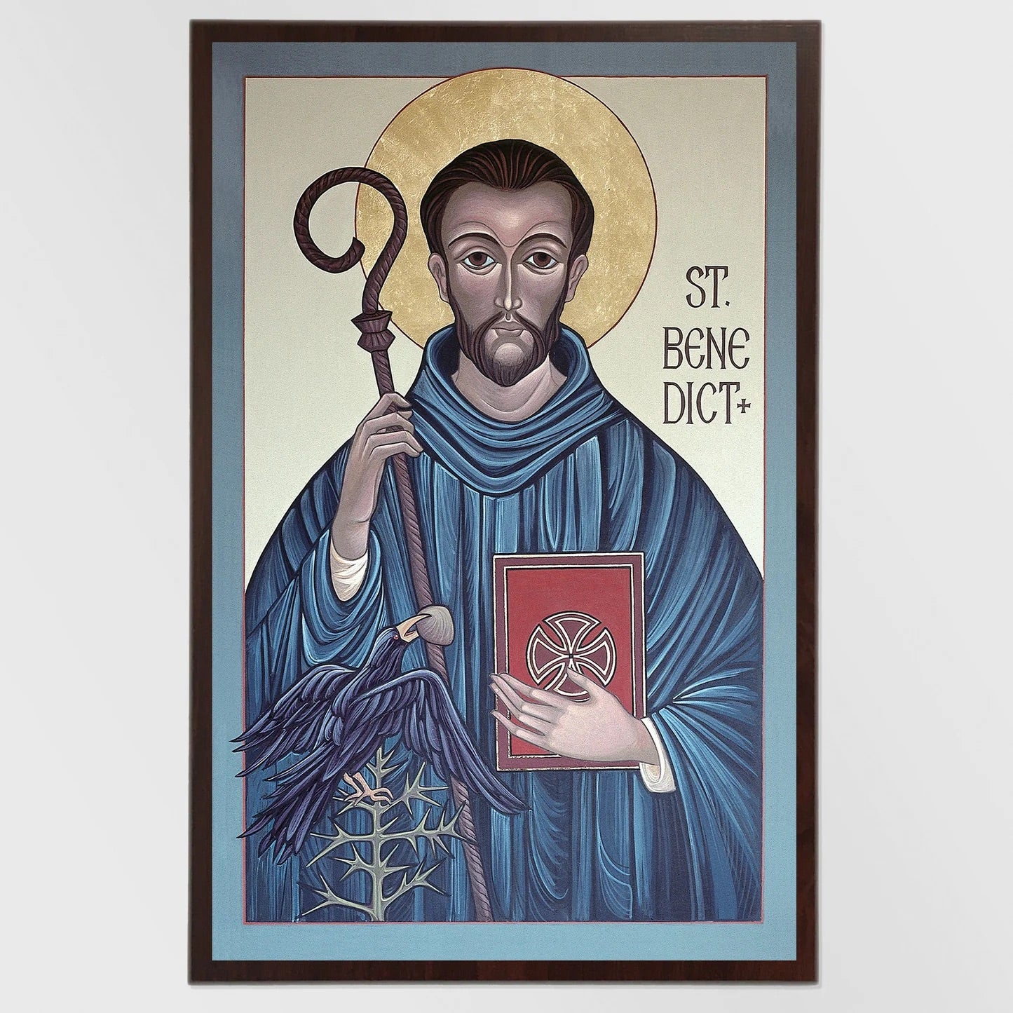 Framed artwork of Saint Benedict holding a book and staff on a light blue background