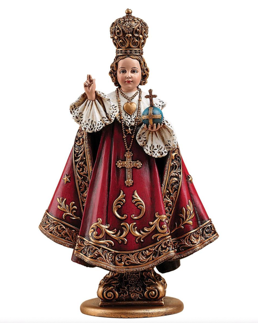 Decorative religious figurine Infant of Prague which is the child Jesus with a crown and red robe on a white background.