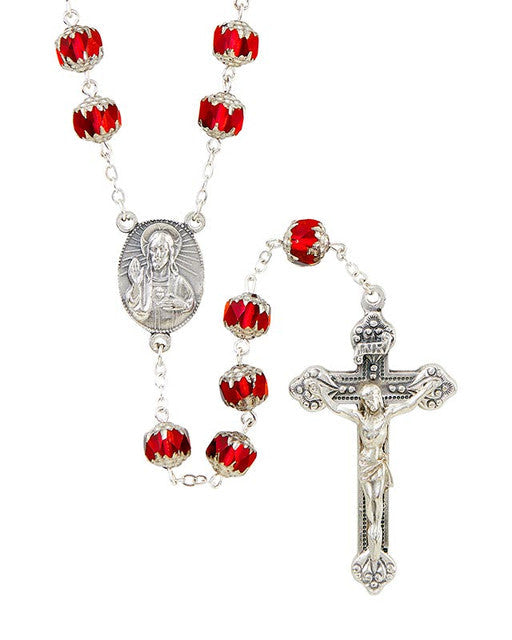 A rosary with red glass beads and silver detailing, featuring an image of Jesus Christ on the center piece and a silver crucifix.