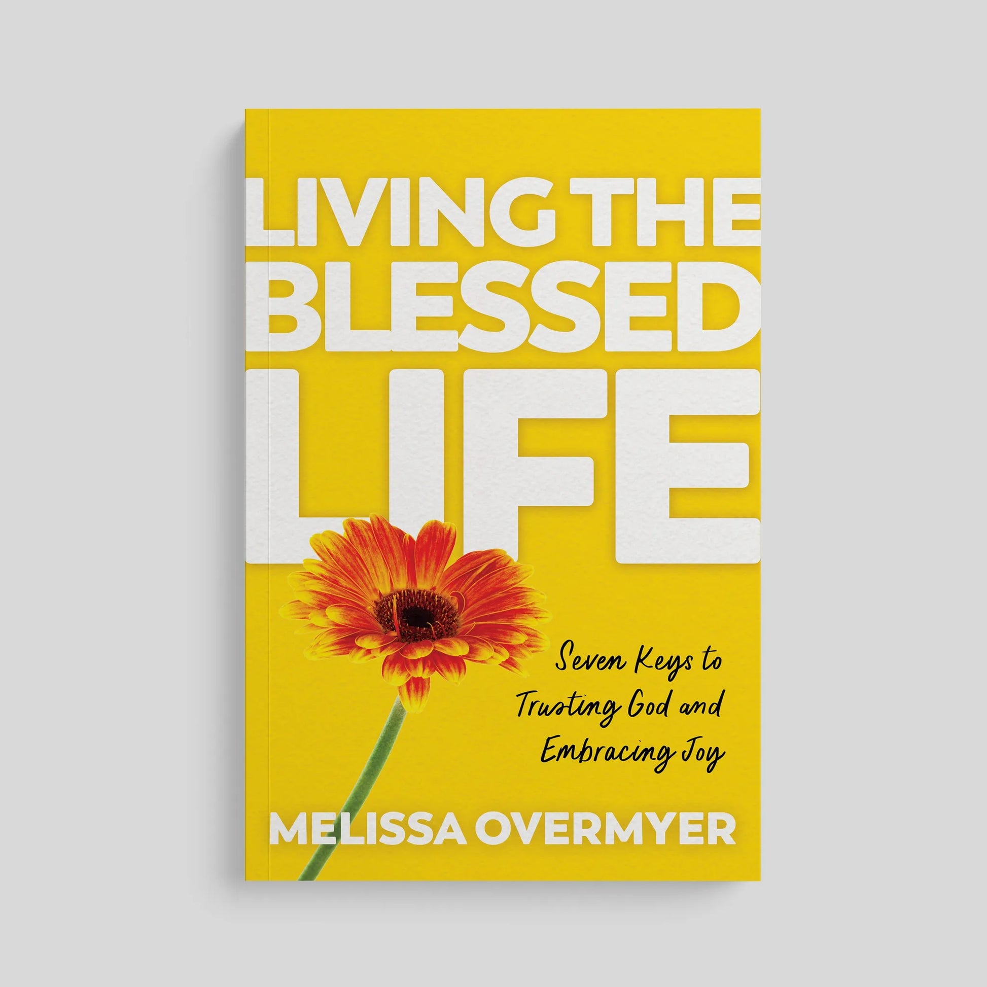 Book cover of 'Living the Blessed Life' with a yellow background and red flower.