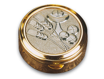 A round gold-toned metal container or medallion with a textured silver-toned insert featuring an embossed wheat stalk and chalice motif, shown on a plain white background.