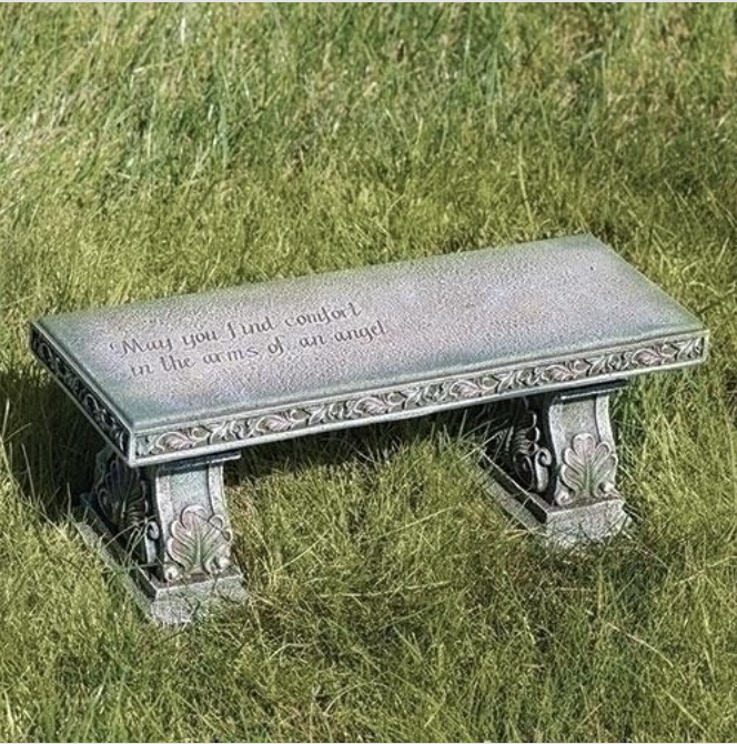 Decorative stone bench with engraved text on a grassy background