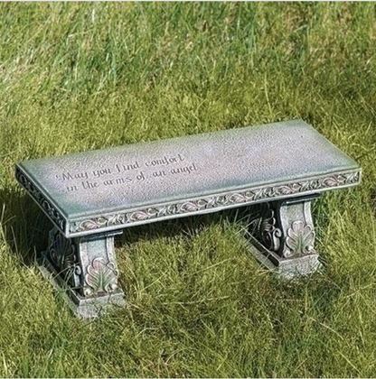 Decorative stone bench with engraved text on a grassy background