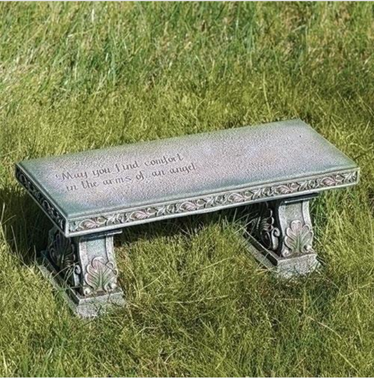 Decorative stone bench with engraved text on a grassy background