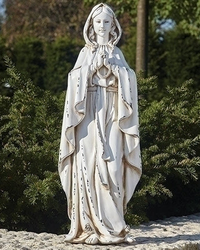 Statue of a religious figure in a natural setting with trees in the background