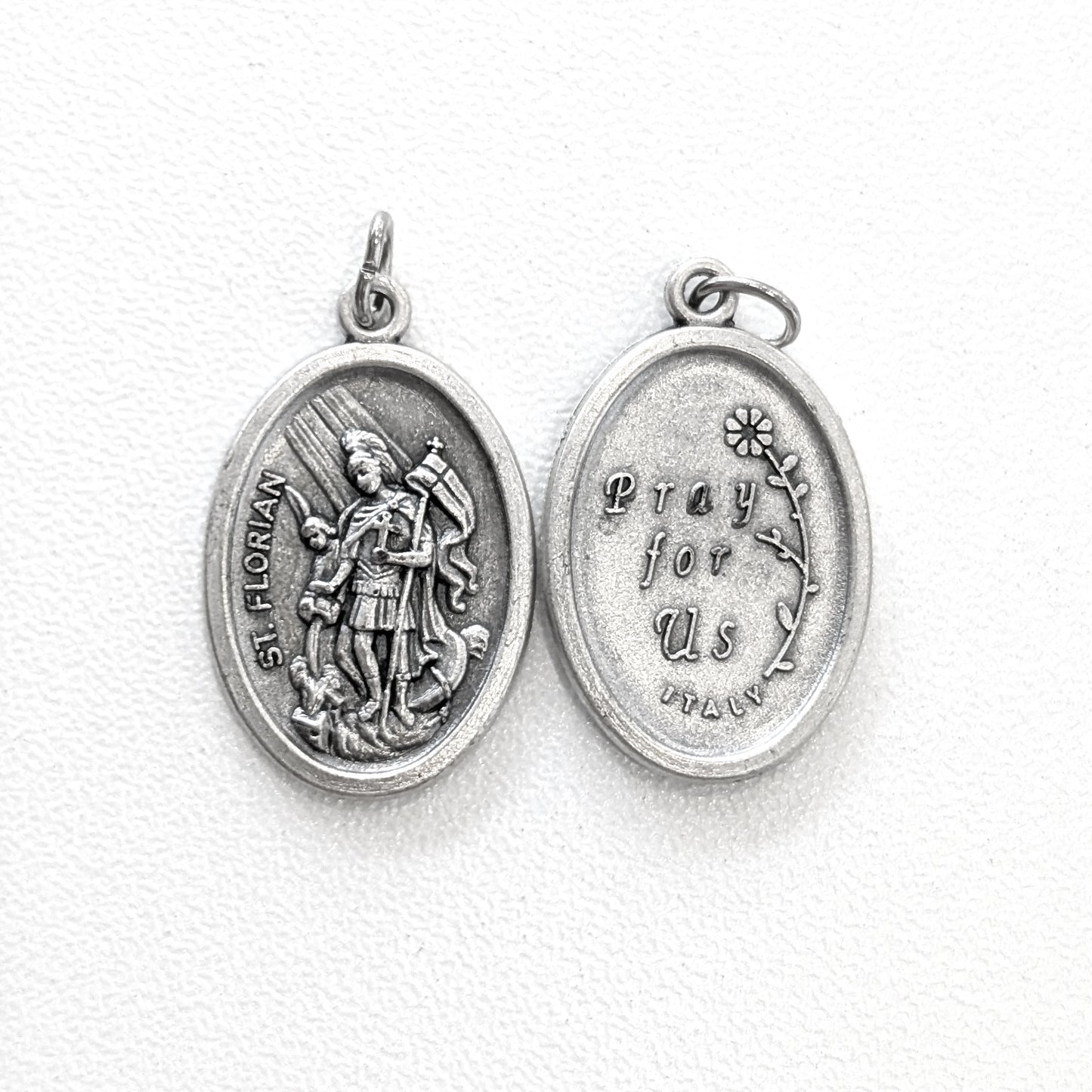 Silver religious pendant with engraved design on a white background