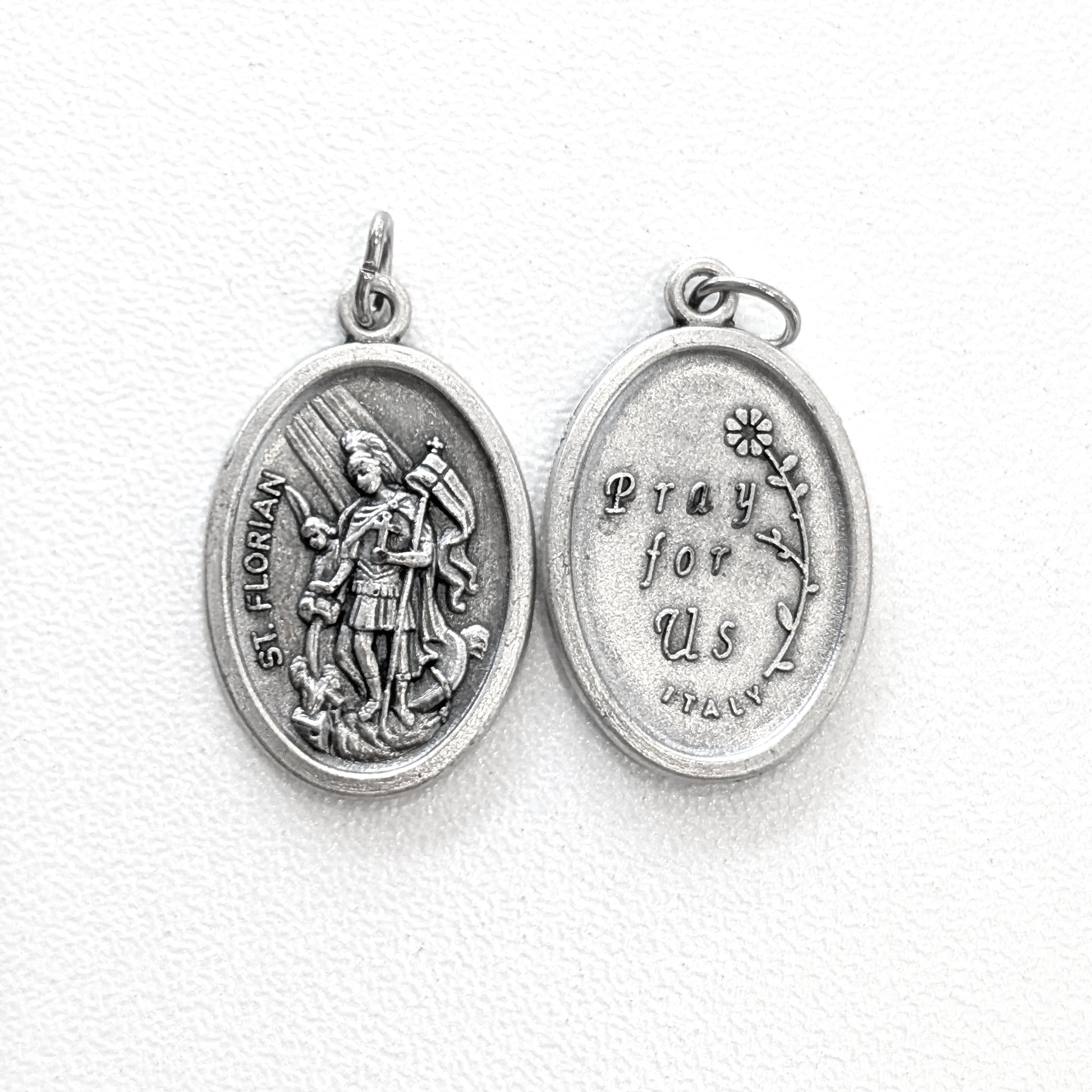 Silver religious pendant with engraved design on a white background