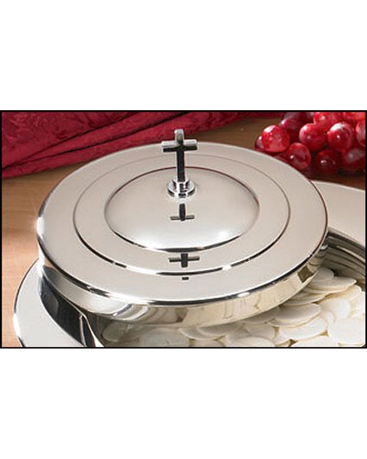 Silver communion wafer tray with cross design on a white background