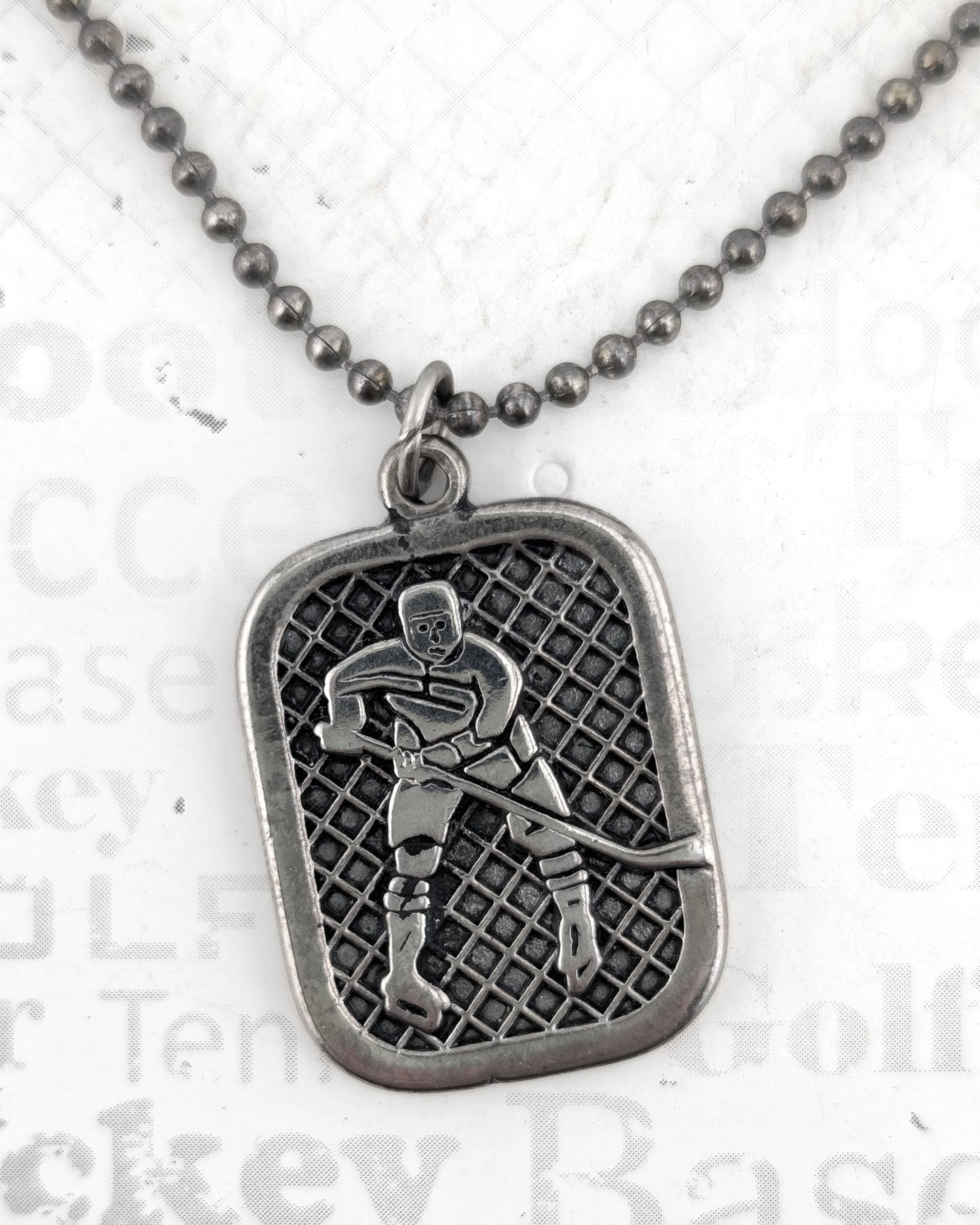 Silver pendant with a hockey player design on a chain against a white background.
