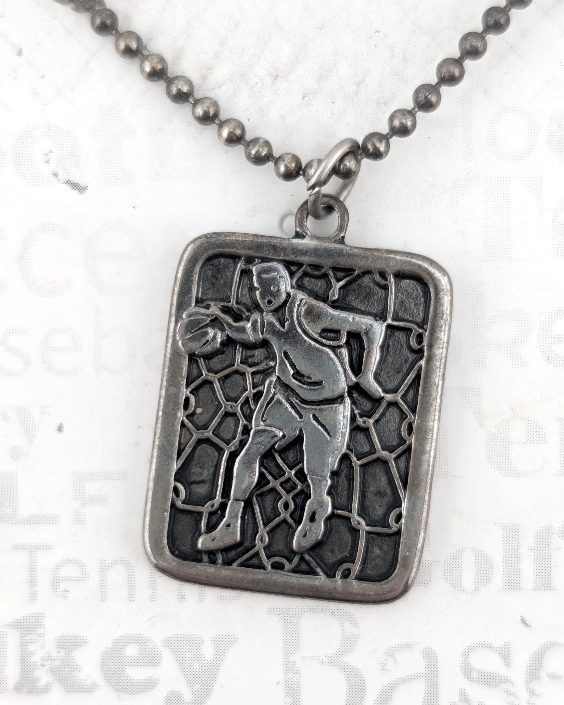 Silver pendant with a detailed design on a chain against a light background