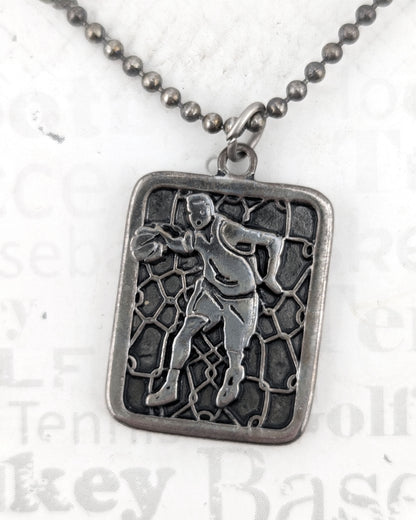 Silver pendant with a detailed design on a chain against a light background