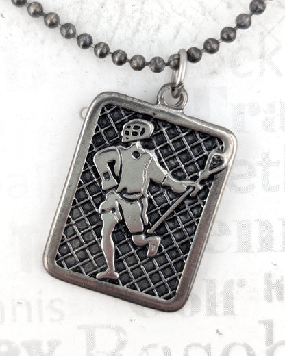 Silver pendant with a grid pattern and figure on a white background