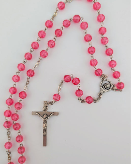 Pink rosary with a silver cross on a white background