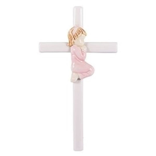 A white porcelain wall cross featuring a central figure of a baby girl in a pink dress praying, with a gold-colored cross and a white background.