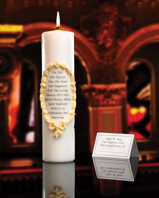 White candle with gold emblem and text in front of a blurred decorative background