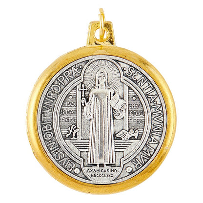 A round metal St. Benedict medal with gold tone rim and antique silver tone.