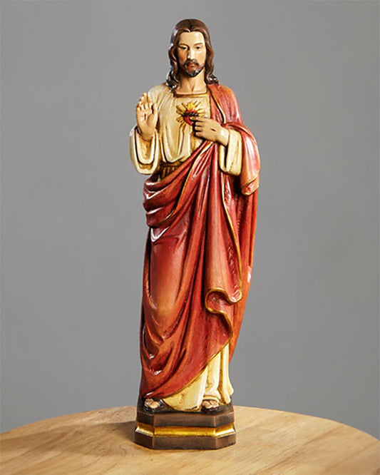 A hand-painted 12-inch statue of the Sacred Heart, made of resin, showing Jesus Christ with a red drape over his shoulders and a golden background.