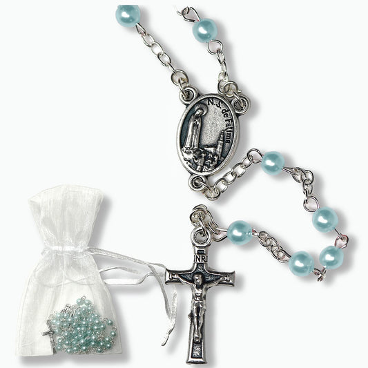 Silver rosary with light blue beads and a white pouch containing more beads on a white background
