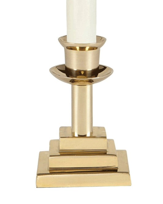 Gold candle holder with a white candle on a white background