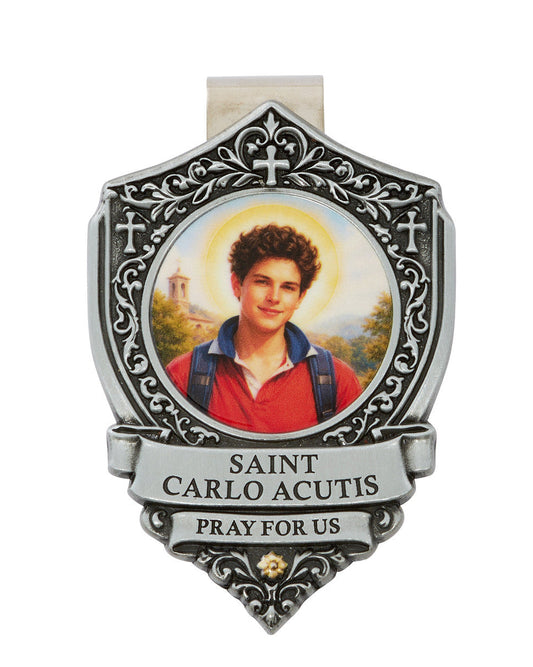A silver-toned metal Saint Carlo Acutis money clip with an ornate shield design, featuring a photo of Saint Carlo Acutis in a red shirt and blue backpack, with a yellow halo. The clip is inscribed with 'SAINT CARLO ACUTIS' and 'PRAY FOR US'.
