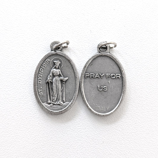Silver religious pendant with a figure and 'Pray for Us' text on a white background