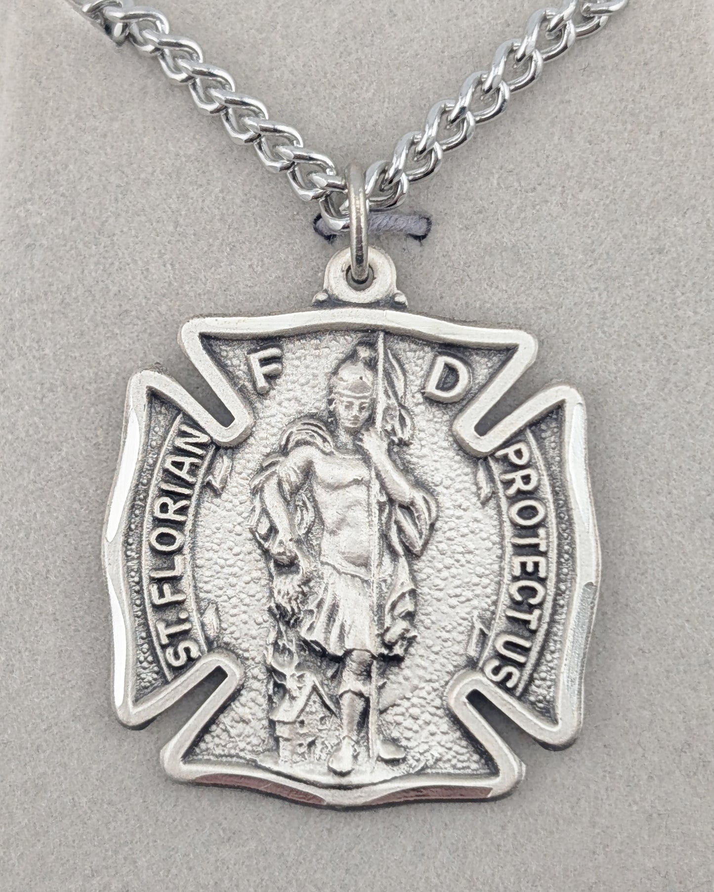 Silver pendant with a religious figure on a gray background