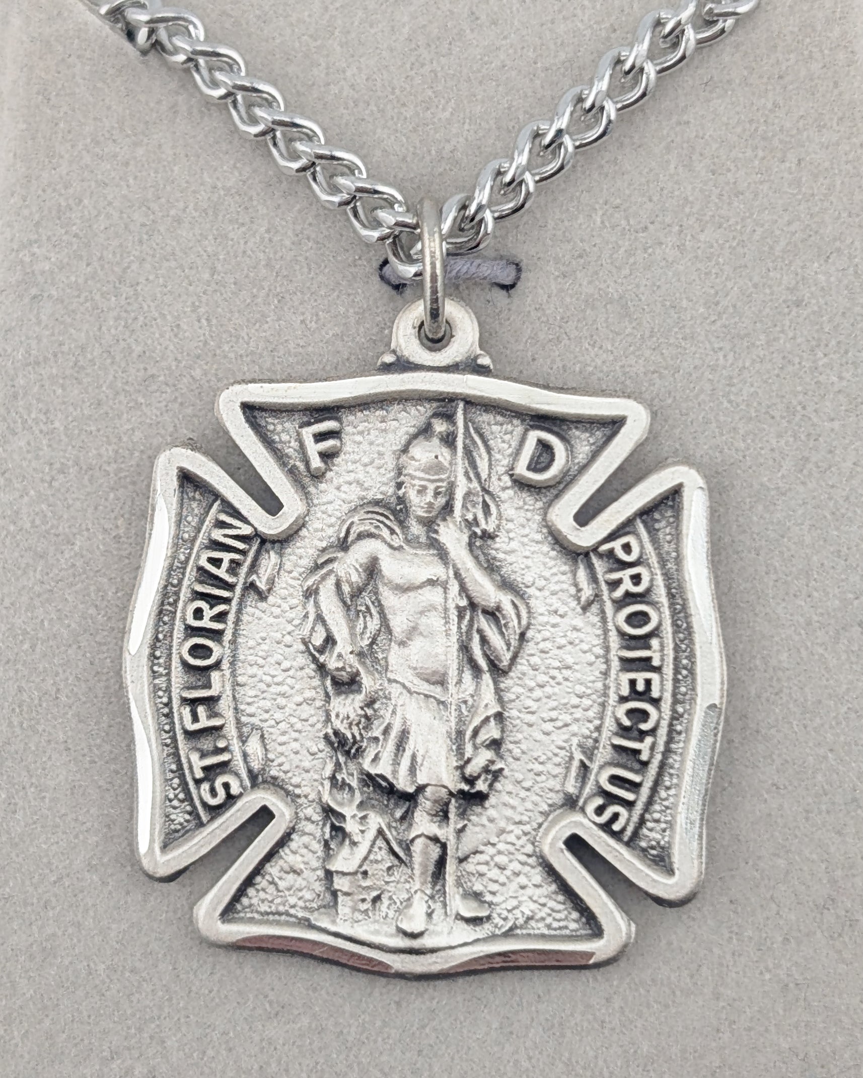 Silver pendant with a religious figure on a gray background