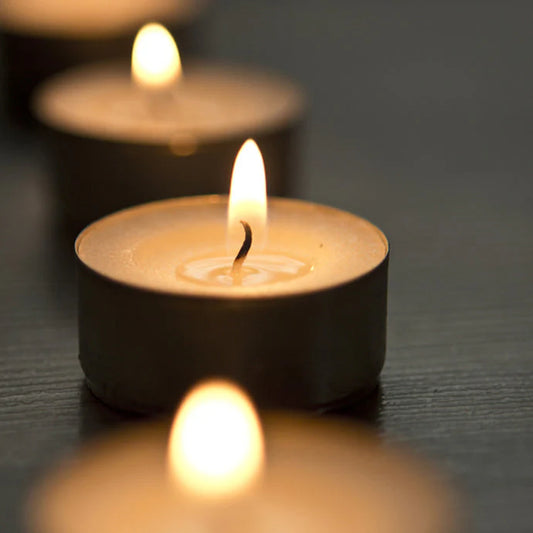 Close-up of three small candles with flames on a dark surface