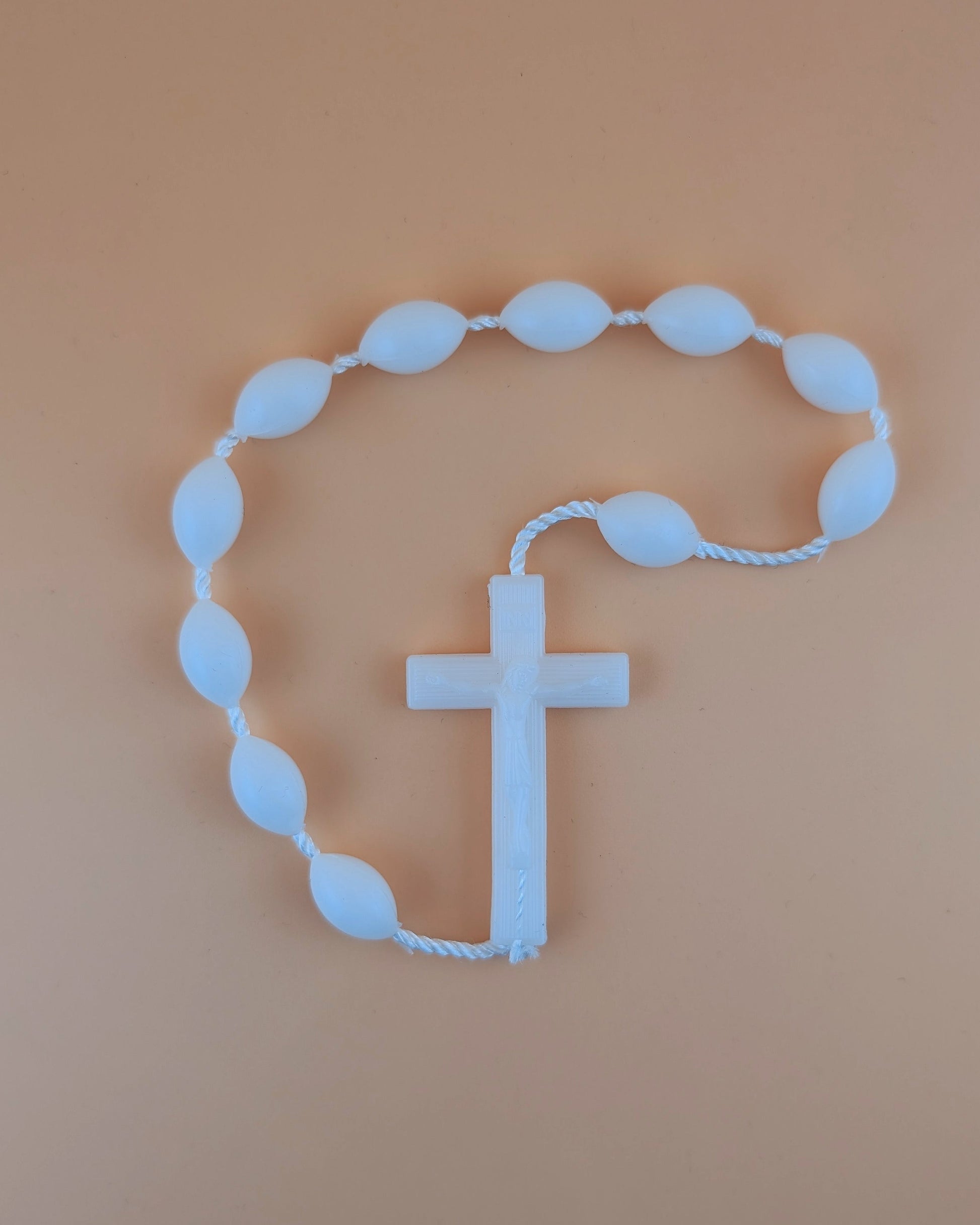 White rosary with a cross on a beige background