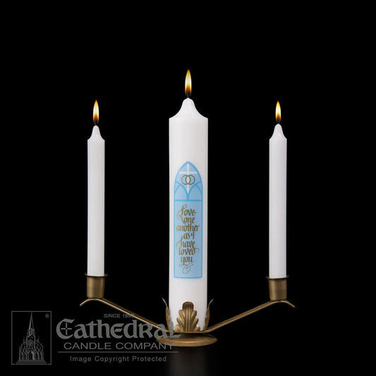 Three candles in a holder with a blue design on one candle against a black background, featuring the Cathedral Candle Company logo.