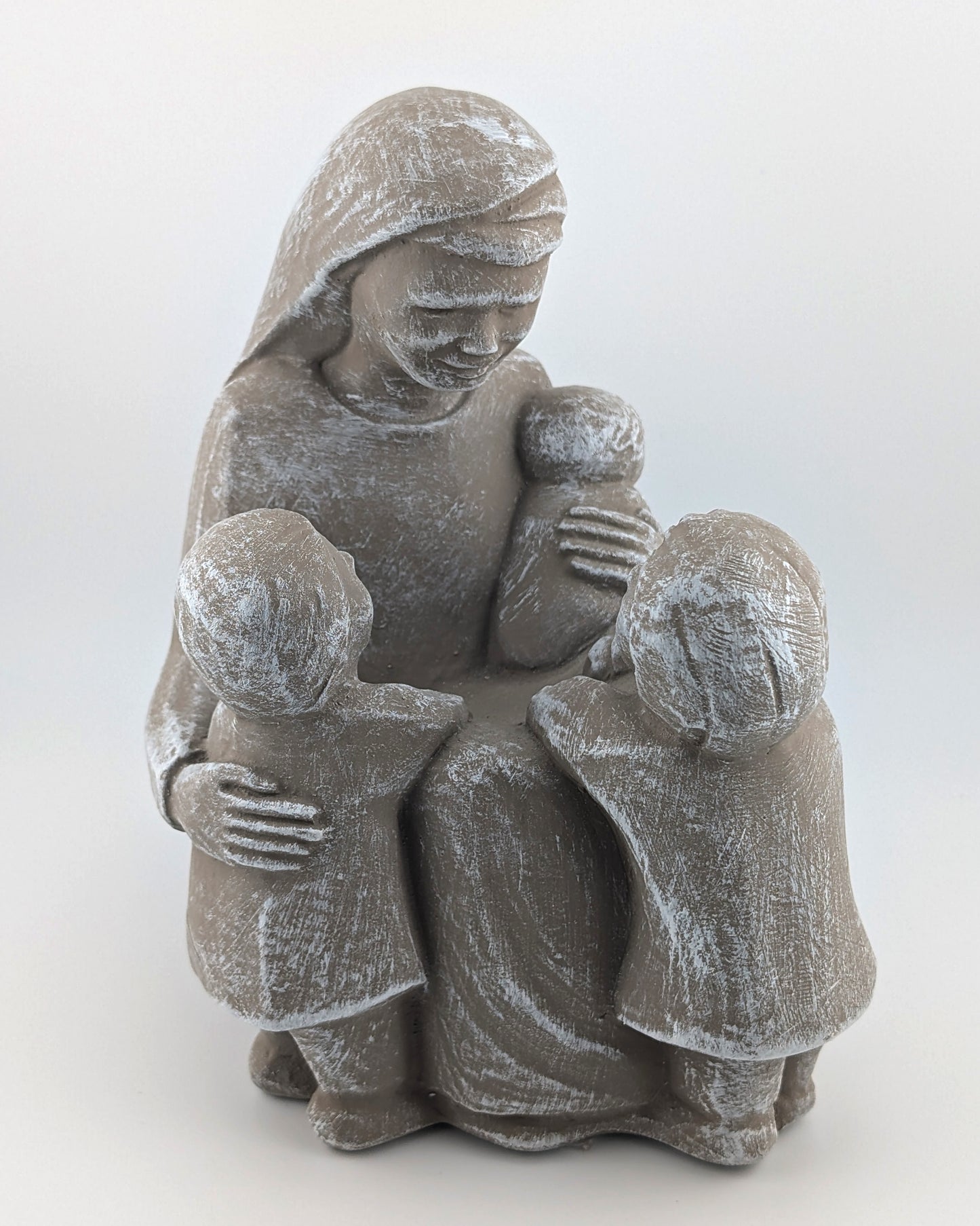 Stone sculpture of a mother holding two children on a white background