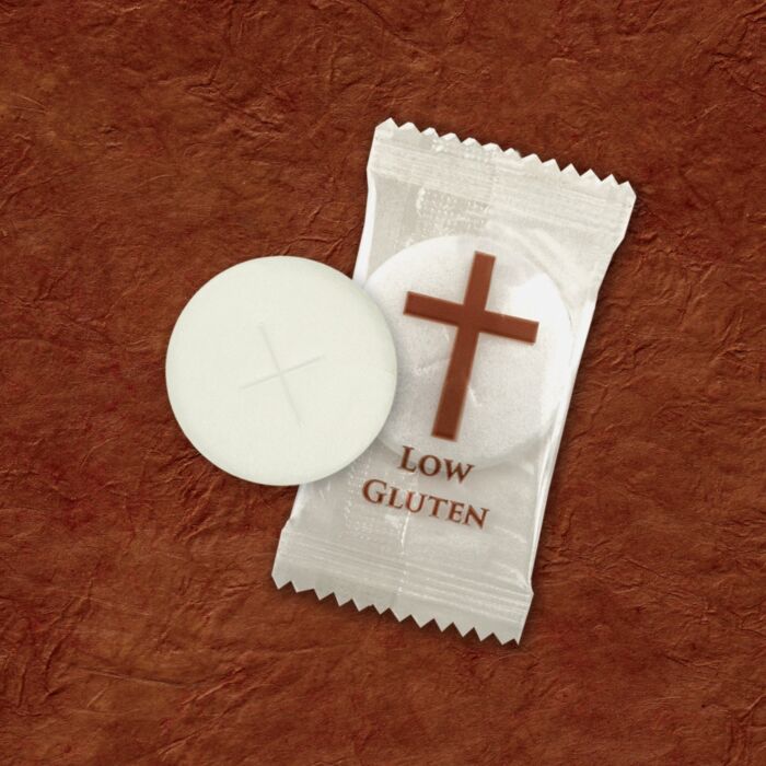 Low gluten wafer with a cross symbol on a textured brown background