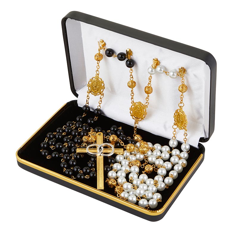 A wedding lasso rosary displayed in an open gift box with black interior, featuring gold-plated elements and black and white beads.