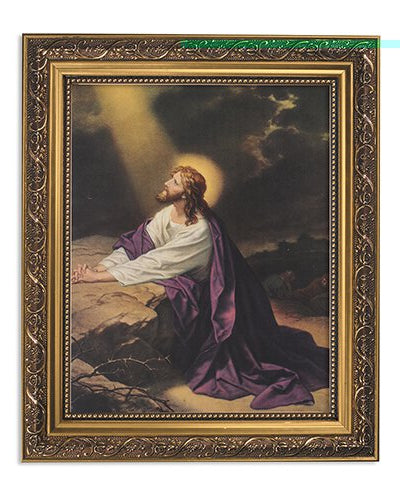 A gold framed picture depicting a religious scene with a figure prayed upon a mountainous landscape.