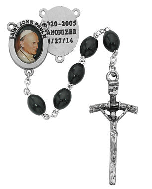 A St. John Paul Rosary with a silver-colored crucifix, red enamelled center, and black wooden beads.