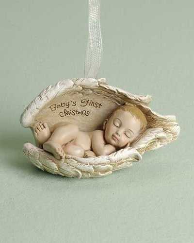 A resin ornament featuring a sleeping baby figure with 'Baby's First Christmas' engraved above. The ornament is beige in color, shaped like a small bed, and has a ribbon for hanging.