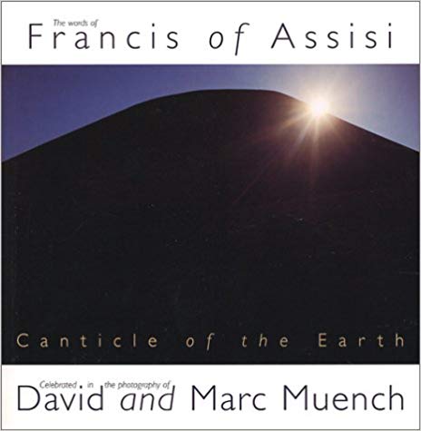 Cover of the book 'The Words of Francis of Assisi: Canticle of the Earth' featuring a photograph of a sun setting behind a silhouetted mountain.