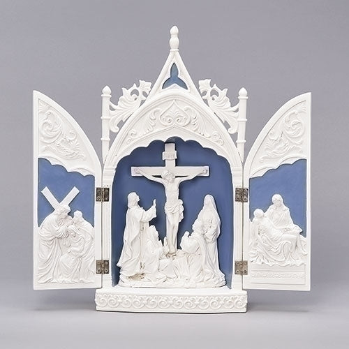A white triptych statue depicting the Passion of Christ with blue backgrounds between the panels.