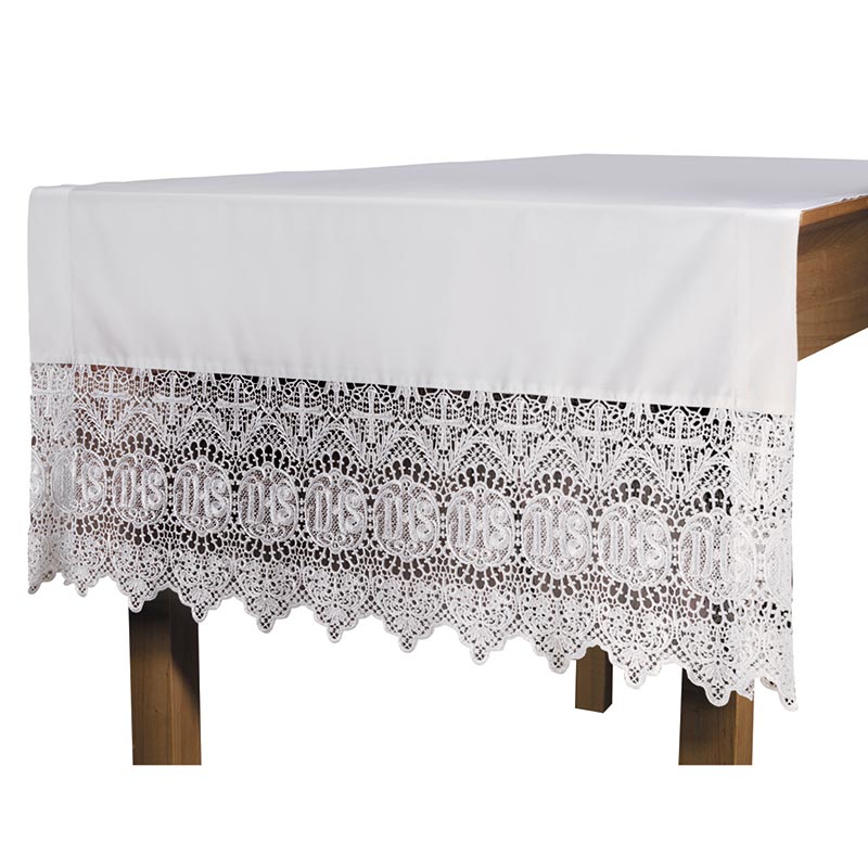 White altar frontal with lace edging and a cross design in the center, displayed on a wooden altar.