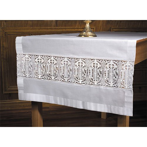 A white altar frontal with lace inserts and the Latin cross design displayed on a wooden altar.