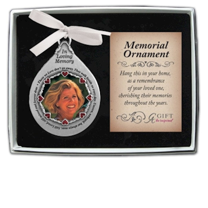 A silver teardrop frame memorial ornament with a photo of a woman, decorated with red heart crystals, a card, and a gift box.