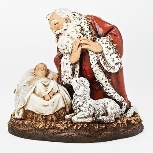 A hand-painted kneeling Santa statue with intricate details, predominantly in red and white colors, beside a nativity scene setting.