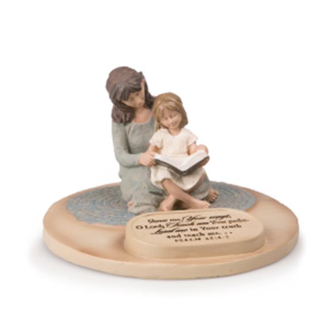 A statue of a mother and daughter sitting together, with the mother reading a book to the daughter. The statue is placed on a circular base, and there is a text plaque on the base as well.
