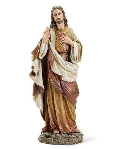 A statue of the Sacred Heart of Jesus, standing with hands clasped in prayer, predominantly beige and brown with a multicolored robe.
