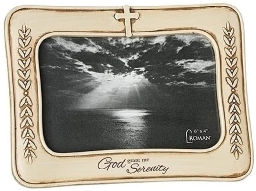 A photo frame with a beige border and a cross motif at the top, containing a black and white photo of a serene natural scene. There is text on the frame that reads 'God grant me serenity.