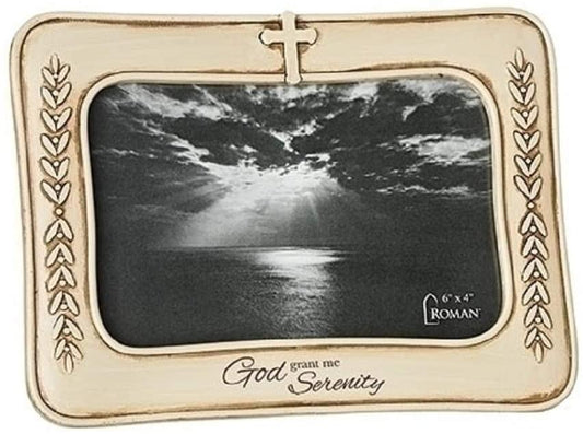A photo frame with a beige border and a cross motif at the top, containing a black and white photo of a serene natural scene. There is text on the frame that reads 'God grant me serenity.