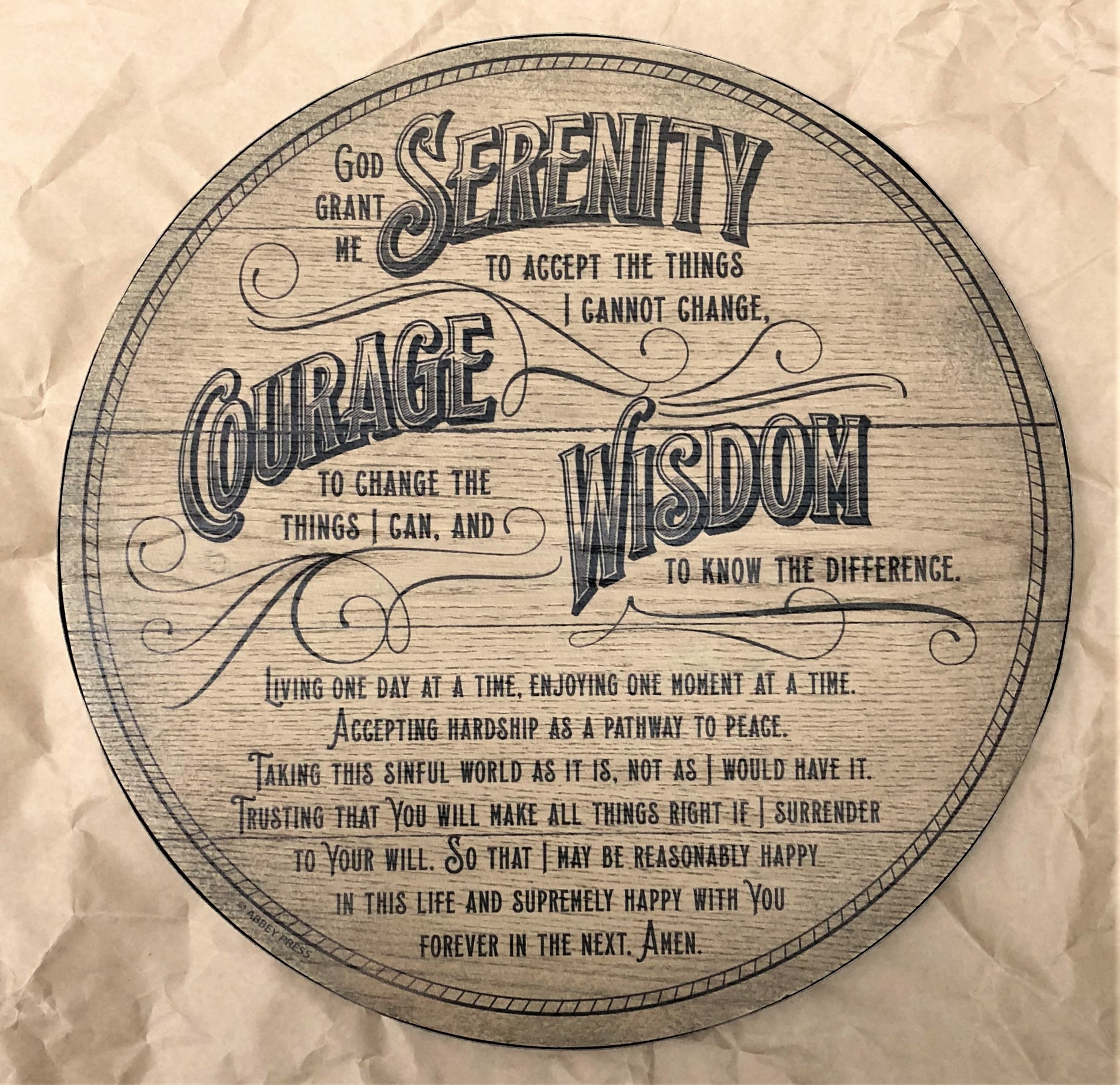 A round MDF board plaque with a rustic barrel-inspired design and copper-colored metal edging. It features the Serenity Prayer in a cursive font.
