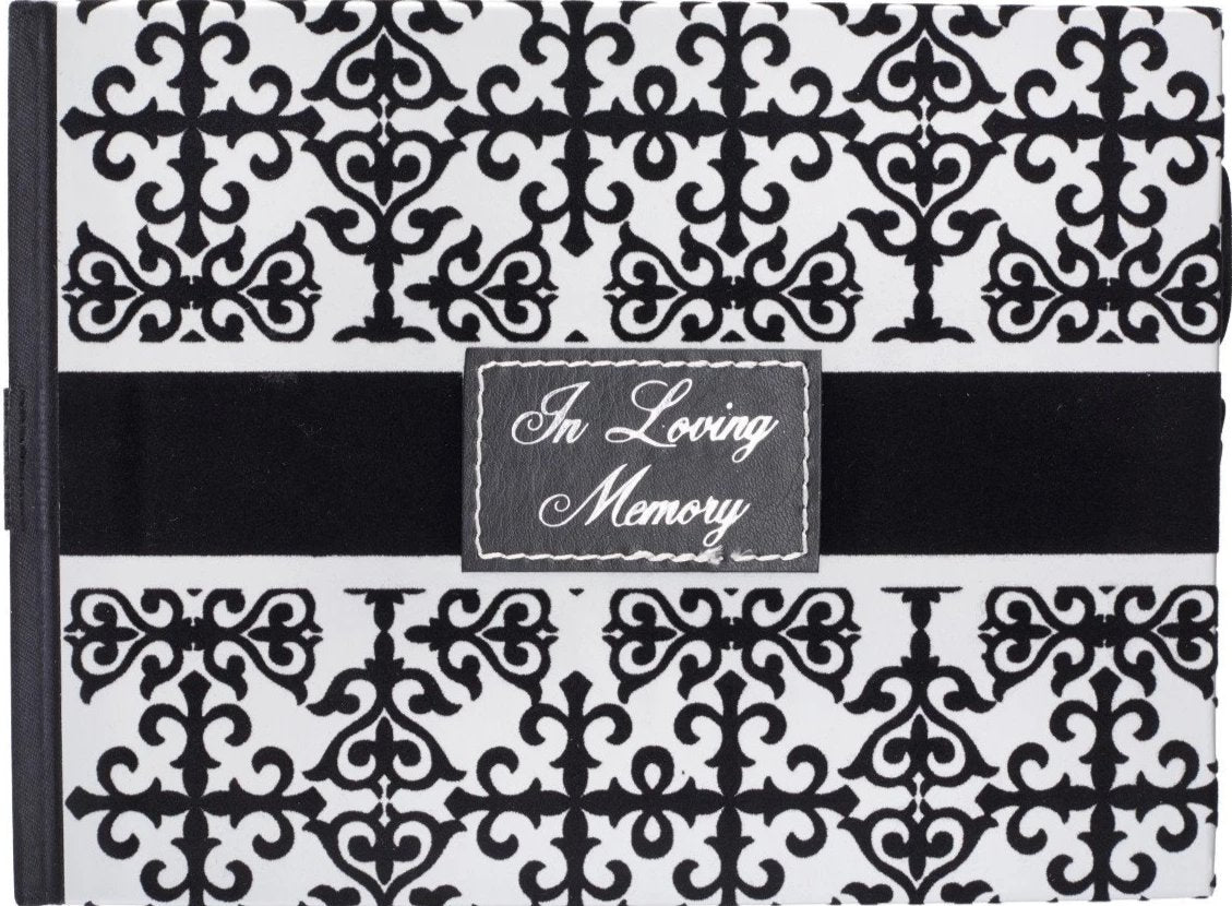 A black and white guest book with a cross design and the title 'In Loving Memory' written on the front cover.