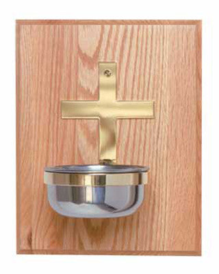 A stainless steel bowl mounted on a solid brass cross, which is affixed to an oak panel.