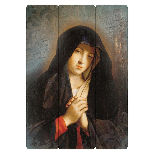 A wooden pallet sign featuring an image of the Virgin Mary in prayer, predominantly in shades of blue and black with a red accent on her garment.